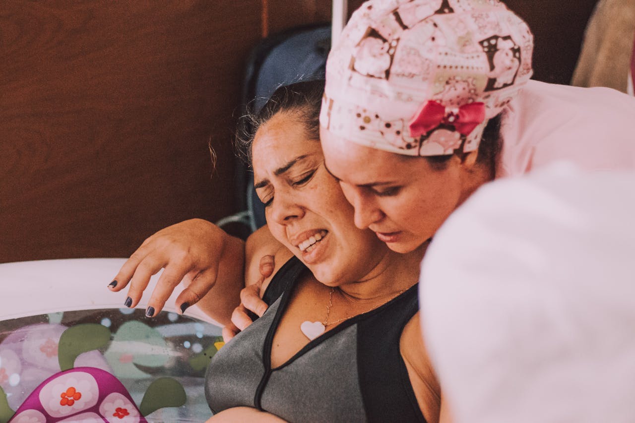 A midwife comforts a pregnant woman during a water birth at home.